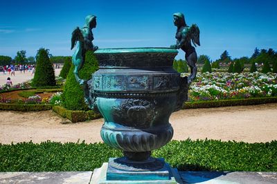 Statue by plants against blue sky