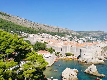 View of buildings by sea against clear blue sky