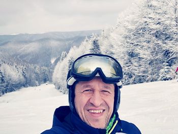 Portrait of smiling man standing on snow covered landscape