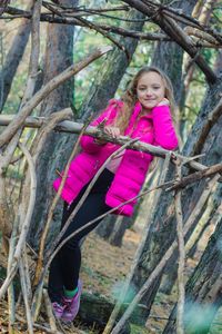 Portrait of smiling girl wearing jacket standing against trees in forest