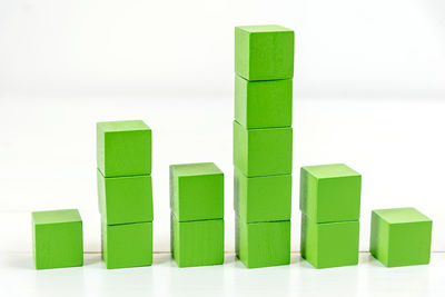 Close-up of stacked green toy blocks on table against white background