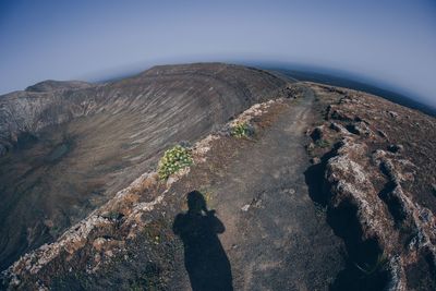 Shadow of man on rock against sky