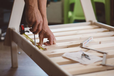 Cropped hands of man measuring wood at home