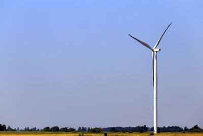 Low angle view of wind turbines on land