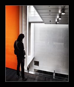 Side view of woman standing against illuminated wall