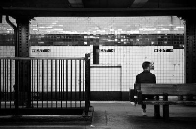 Rear view of man sitting on bench at subway station