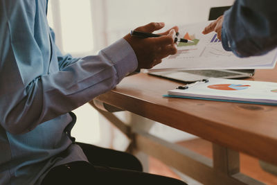 Midsection of businessman and colleagues working over graph on table