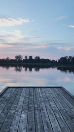 Pier on lake against sky during sunset