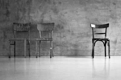 Empty chairs and table against wall in old building