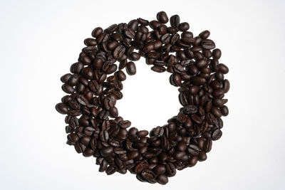 Close-up of heart shape coffee beans against white background