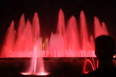 Blurred motion of man against illuminated water at night