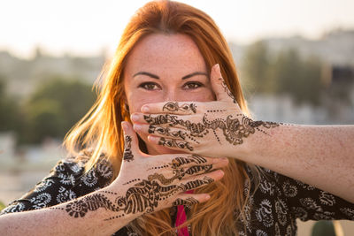 Portrait of young woman showing henna tattoo on hands