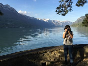 Woman photographing against lake