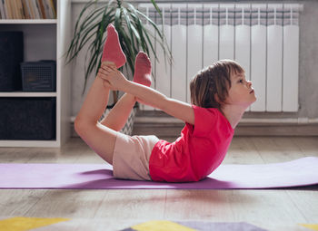 Child performs the exercise gymnastics at home on a mat. home workouts. health and sports.