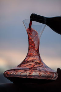 Cropped image of bottle pouring red wine in decanter