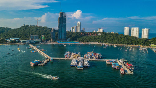 Sailboats in sea by buildings against sky