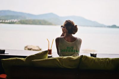 Rear view of woman sitting in front of lake