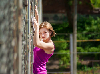 Portrait of beautiful young woman climbing wall