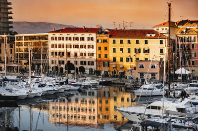 Boats moored at harbor against buildings in city