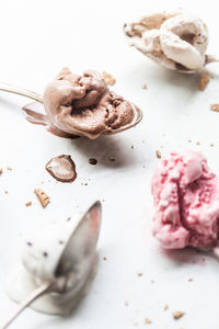 High angle view of various ice creams and spoons on table