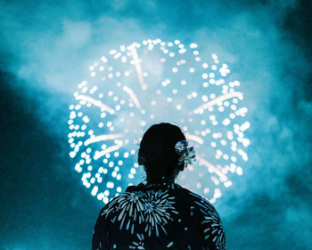 Rear view of silhouette woman looking at firework display