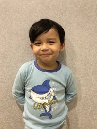 Portrait of smiling boy standing against wall