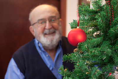 Close-up of christmas tree with senior man standing in background
