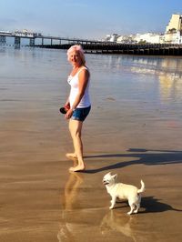 Portrait of woman with puppy walking at beach