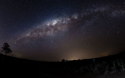 Silhouette landscape against star field at night