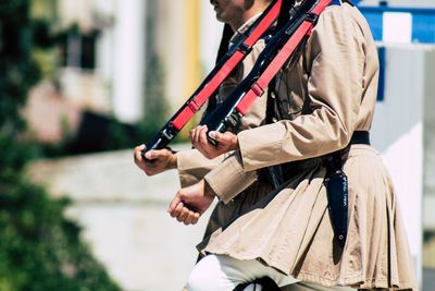 Midsection of man holding camera while standing outdoors
