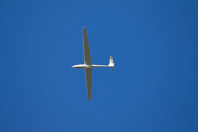 Low angle view of an airplane against clear blue sky