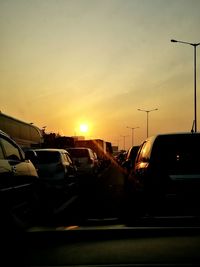 Cars on road against sky during sunset