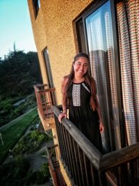 Portrait of smiling young woman standing in balcony