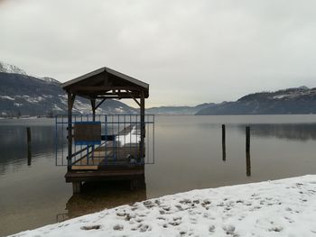 Gazebo by snowcapped mountains against sky during winter