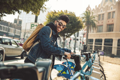 Stylish young man on the street with rental bike