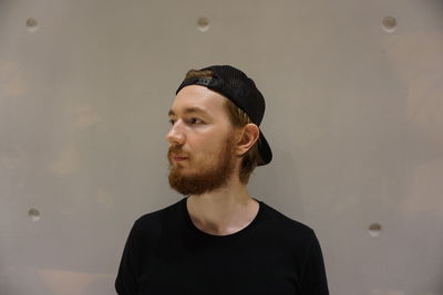 Portrait of young man looking away against wall