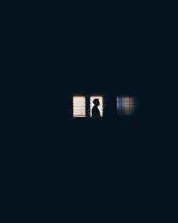 Silhouette man seen through window at night
