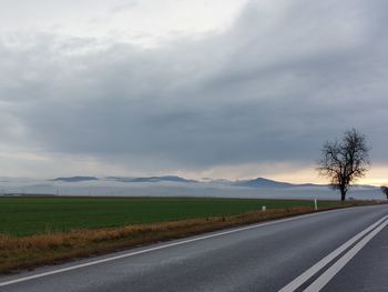 Road amidst field against sky