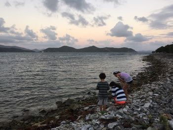 Rear view of children on beach against sky