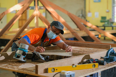 Carpenter wearing mask working at workshop