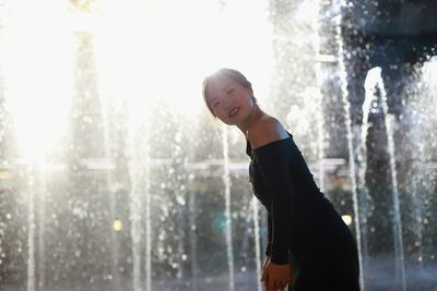 Rear view of woman standing against waterfall