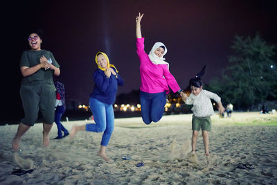 Happy family jumping on beach against sky at night