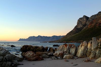 Rocks on beach against sky during sunset