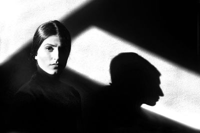 Portrait of woman standing against wall during sunny day