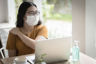 Businesswoman wearing mask looking away while sitting at cafe