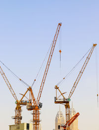 Low angle view of cranes against clear sky