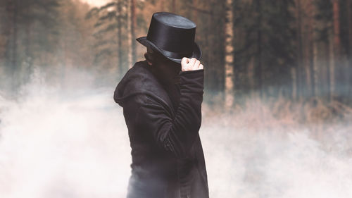 Man wearing hat standing in fog