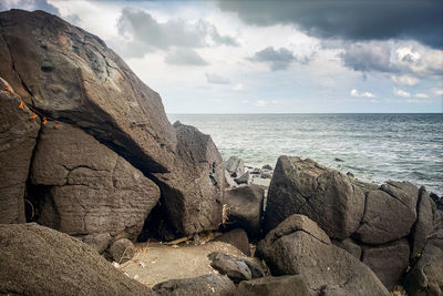 Rock formation on beach against sky