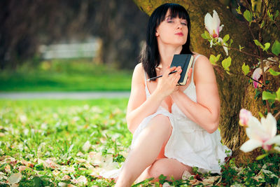 Beautiful young woman sitting on grass