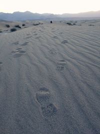 Scenic view of sand dunes at beach against sky